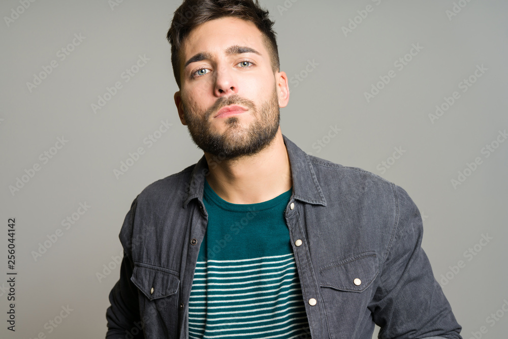 Fototapeta premium Young handsome man possing and modeling over grey isolated background