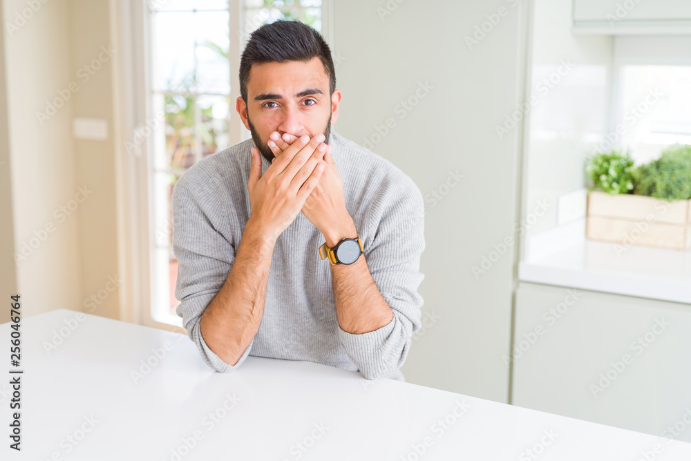 Handsome hispanic man wearing casual sweater at home shocked covering mouth with hands for mistake. Secret concept. Handsome hispanic man wearing casual sweater at home shocked covering mouth with hands for mistake. Secret concept.