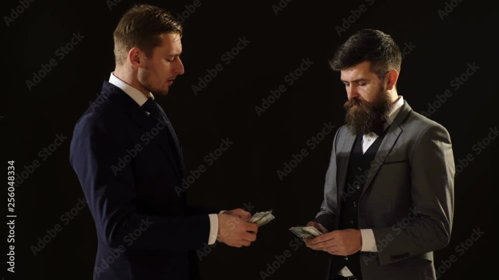 Business concept. Two corrupt officials count money from shadow operations. Two men in costumes count money on a black background. Business concept. Two corrupt officials count money from shadow operations. Two men in costumes count money on a black background.