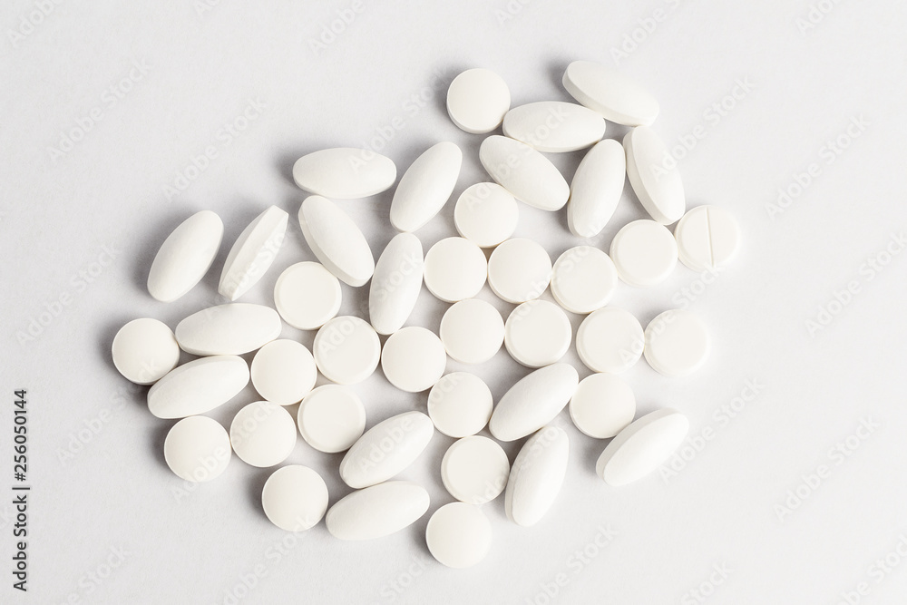 Close up of a group of white pills isolated on white background, in random order