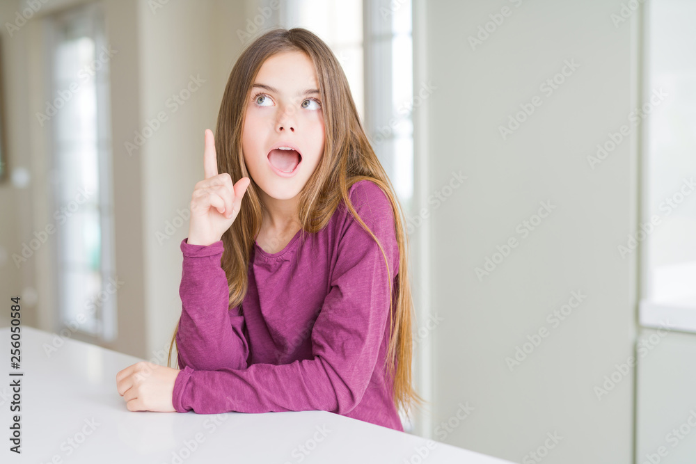 Beautiful young girl kid on white table pointing finger up with successful idea. Exited and happy. Number one. Beautiful young girl kid on white table pointing finger up with successful idea. Exited and happy. Number one.