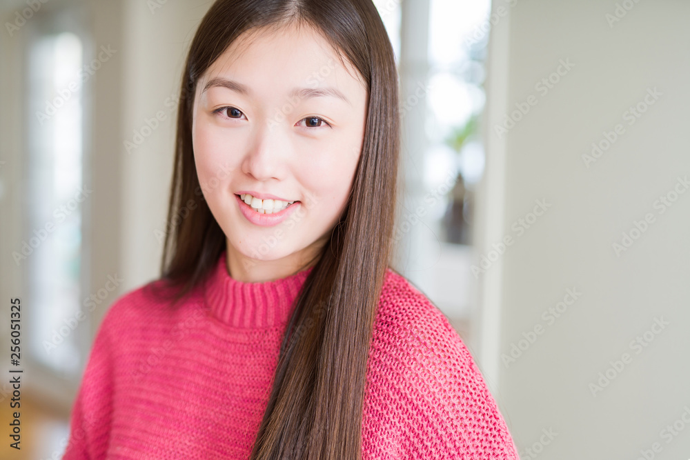Beautiful Asian woman wearing pink sweater with a happy and cool smile on face. Lucky person.