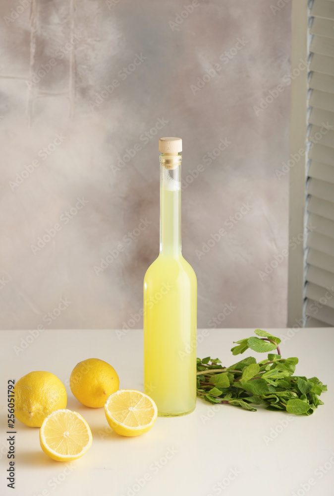 Bottle of homemade juice with mint and lemon on light background. Vertical Bottle of homemade juice with mint and lemon on light background. Vertical