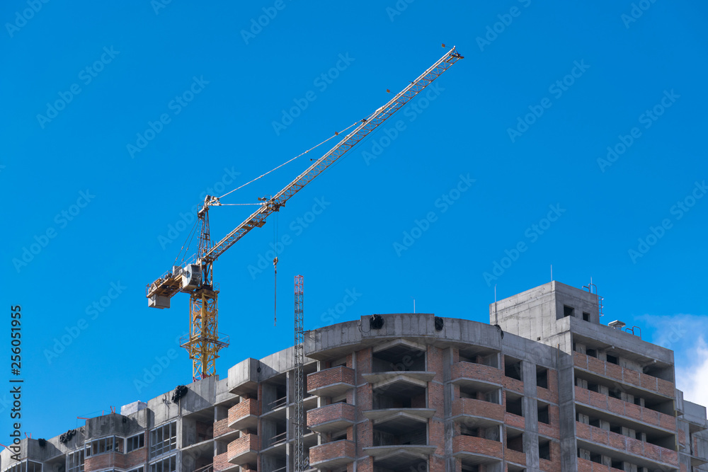 construction crane is building a new home skyscraper on a background of blue sky