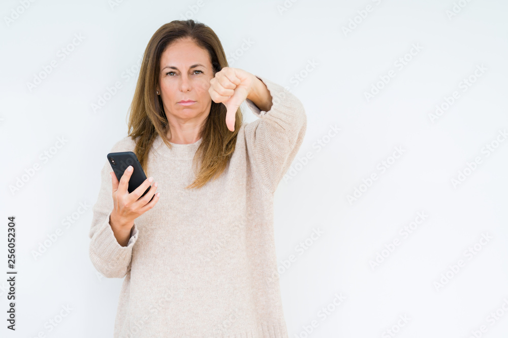 Middle age woman using smartphone over isolated background with angry face, negative sign showing dislike with thumbs down, rejection concept Middle age woman using smartphone over isolated background with angry face, negative sign showing dislike with thumbs down, rejection concept
