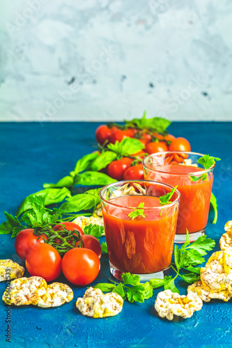 Red cocktail with tomato juice between tomatoes, basil, parsley and nutritious cereal breads