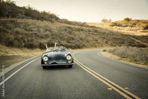 Young couple drive convertible uphill