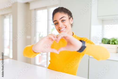 Beautiful young african american woman with afro hair smiling in love showing heart symbol and shape with hands. Romantic concept.