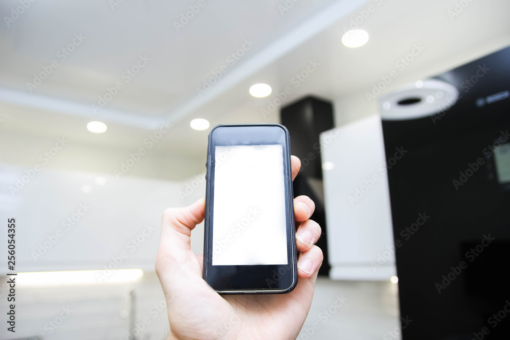 Smartphone with white screen in the kitchen, smart home system, concept of energy saving and technological lighting control. Smartphone with white screen in the kitchen, smart home system, concept of energy saving and technological lighting control.