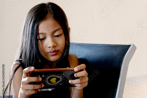 Petite fille asiatique joue avec un smartphone très concentrée