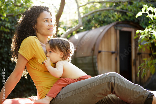 Toddler breastfeeds in backyard