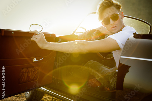 Stylish young man opens door of convertible