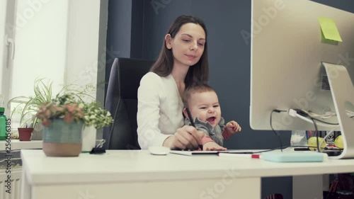 Working mother with toddler at baby friendly office, working sucsessful female entrepreneur modern motherhood photo