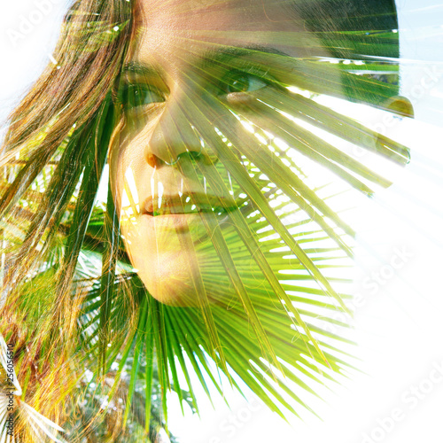 Double exposure close up of a young happy natural beauty and tropical leaves with rays of bright sunlight shining through them