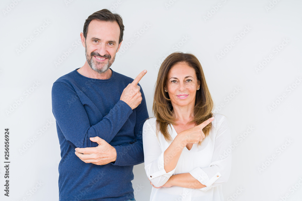 Beautiful middle age couple in love over isolated background Pointing with hand finger to the side showing advertisement, serious and calm face Beautiful middle age couple in love over isolated background Pointing with hand finger to the side showing advertisement, serious and calm face