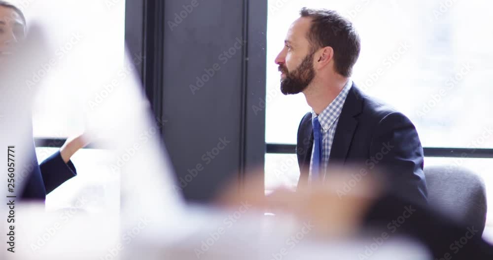 4K Smiling business man & woman talking in sunlit office with soft focus foreground