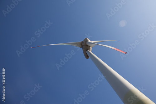 wind turbine with sun flare blue sky background view from below photo