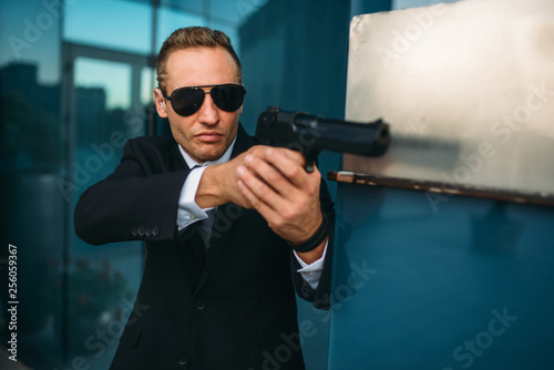 Bodyguard in suit and sunglasses with gun in hands