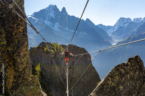 Mountaineer crossing cable bridge via ferrata, Chamonix France.