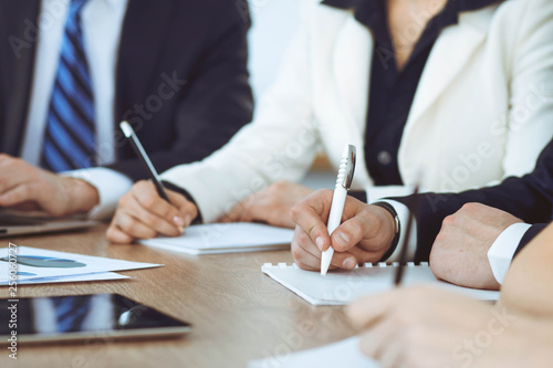 Group of business people or lawyers work together at meeting in office, hands using tablet and making notes close-up. Negotiation and communication concept