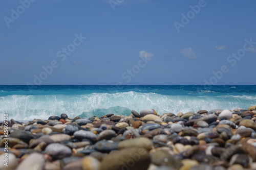 Clear azure wave covers Natural Round Pebbles On The Beach