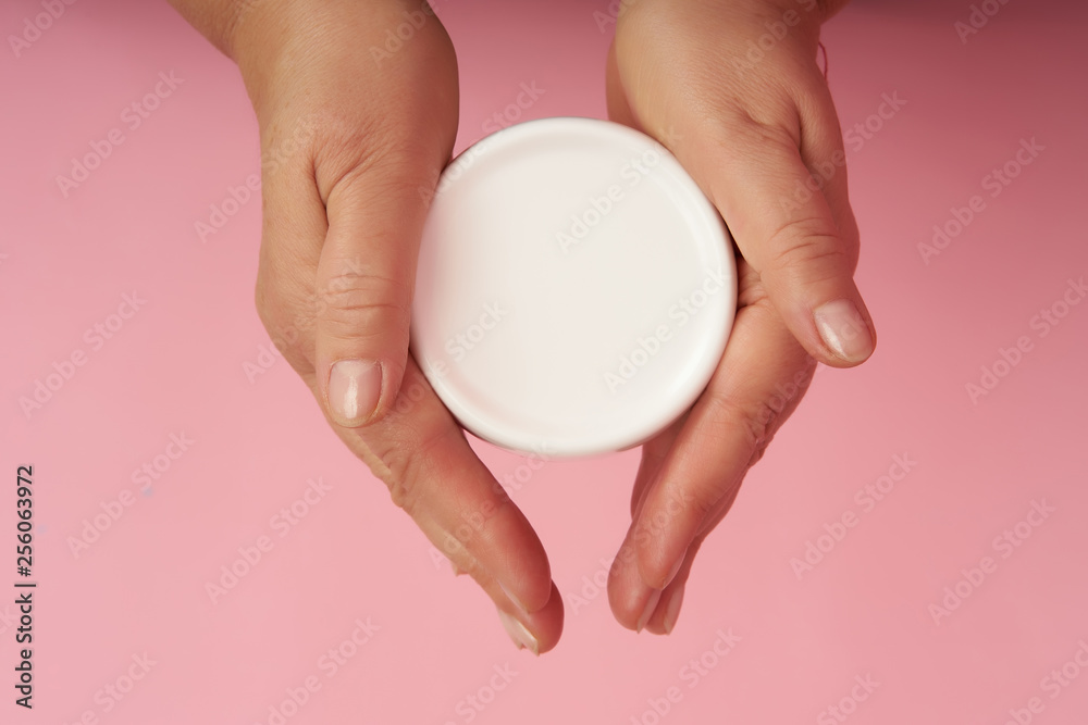 Senior woman's hands are holding cream for hands on coral background Senior woman's hands are holding cream for hands on coral background
