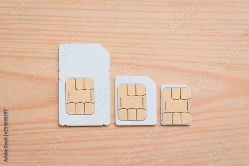 SIM cards of different side on a wooden background. SIM card, micro SIM and nano SIM on table