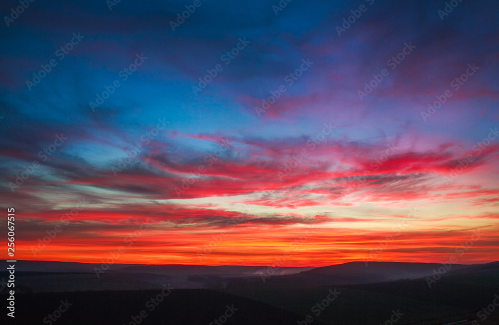 Colorful magnificent sunset in countryside above hills and fields, beauty nature background