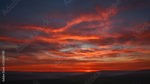 Colorful magnificent sunset in countryside above hills and fields, beauty nature background © okostia