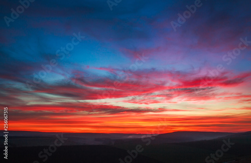 Colorful magnificent sunset in countryside above hills and fields, beauty nature background