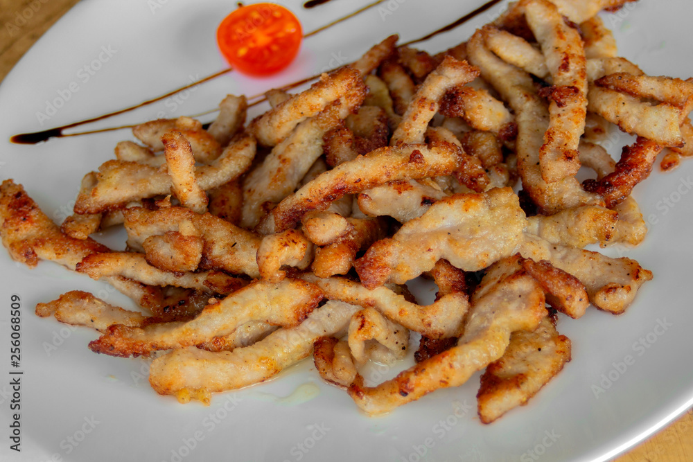Crispy fried pork slices. Garnished with cherry tomatoes and balsamic sauce. Closeup. Crispy fried pork slices. Garnished with cherry tomatoes and balsamic sauce. Closeup.