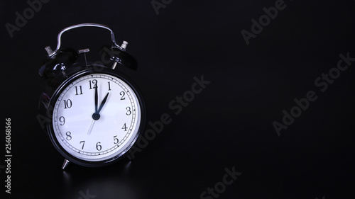 Close up image of old black vintage alarm clock. One o'clock