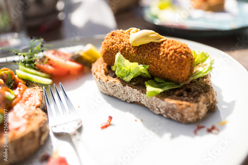 Photography plate with typical meal, fired snack croquet with salad on slice of bread