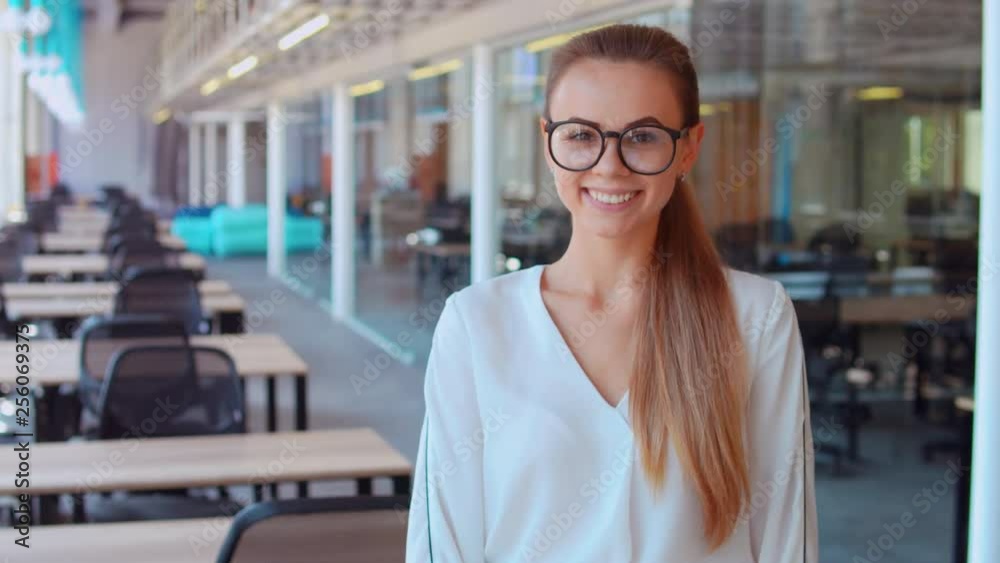portrait happy caucasian elegant business worker posing in open space office. cheerful woman with eyeglasses looking at the camera showing hand gesture like manager with blond hair wears white shirt portrait happy caucasian elegant business worker posing in open space office. cheerful woman with eyeglasses looking at the camera showing hand gesture like manager with blond hair wears white shirt