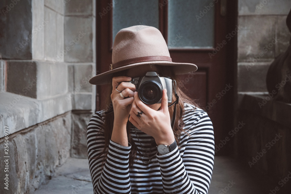 Young beautiful woman in hat is taking picture with old fashioned camera, outdoors Young beautiful woman in hat is taking picture with old fashioned camera, outdoors