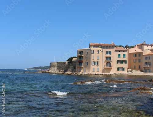 Fototapeta Naklejka Na Ścianę i Meble -  La Ponche Saint-Tropez beach. Blue sky, clear water of the Mediterranean Sea and the stone wall of the historic fortress.