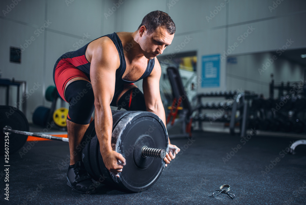 Male powerlifter prepares a barbell in gym Male powerlifter prepares a barbell in gym