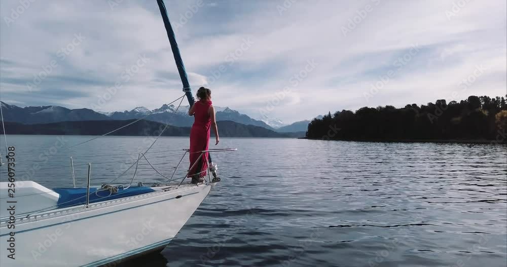 Hispanic woman relaxing on the bow of the sailboat looking at the beautiful Patagonian lake Nahuel Huapi. Aerial view, 4k Hispanic woman relaxing on the bow of the sailboat looking at the beautiful Patagonian lake Nahuel Huapi. Aerial view, 4k