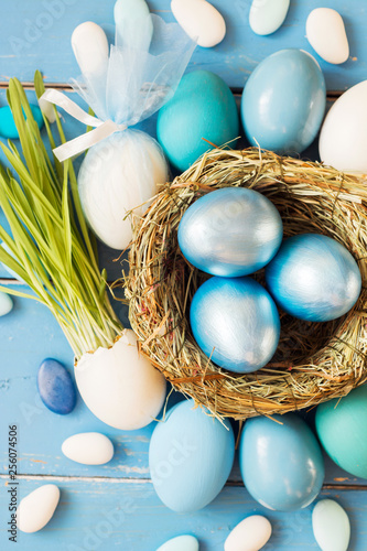 Bright blue colored Easter eggs in nest on wooden background, selective focus image. Happy Easter card 