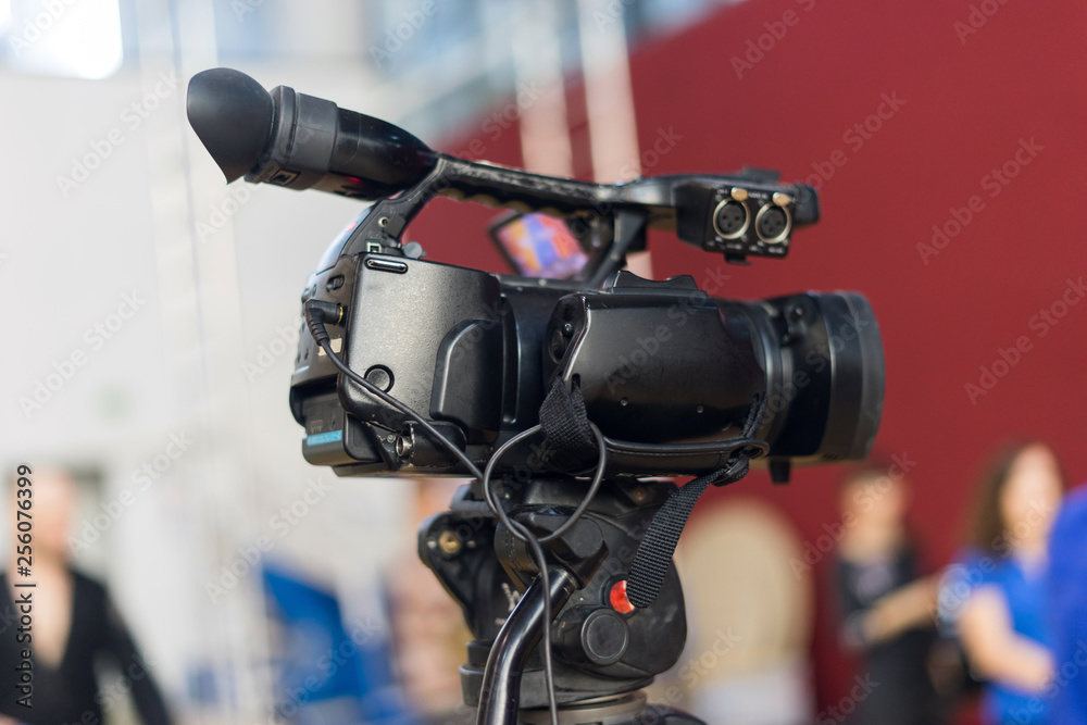 Television camera on the tripod filming recording at the conference