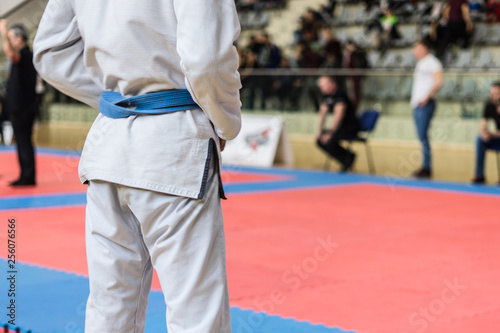 Close up on midsection of judo BJJ fighter holding his blue belt while waiting to compete at the tournament