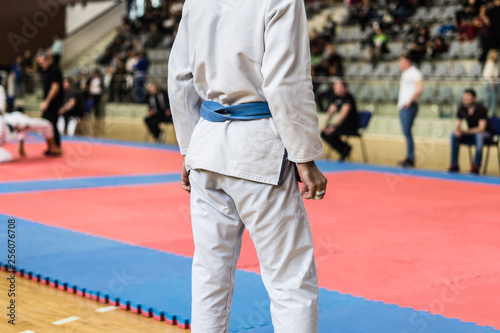 Midsection of Brazilian Jiu JItsu BJJ fighter blue belt while waiting to compete by tatami at the tournament