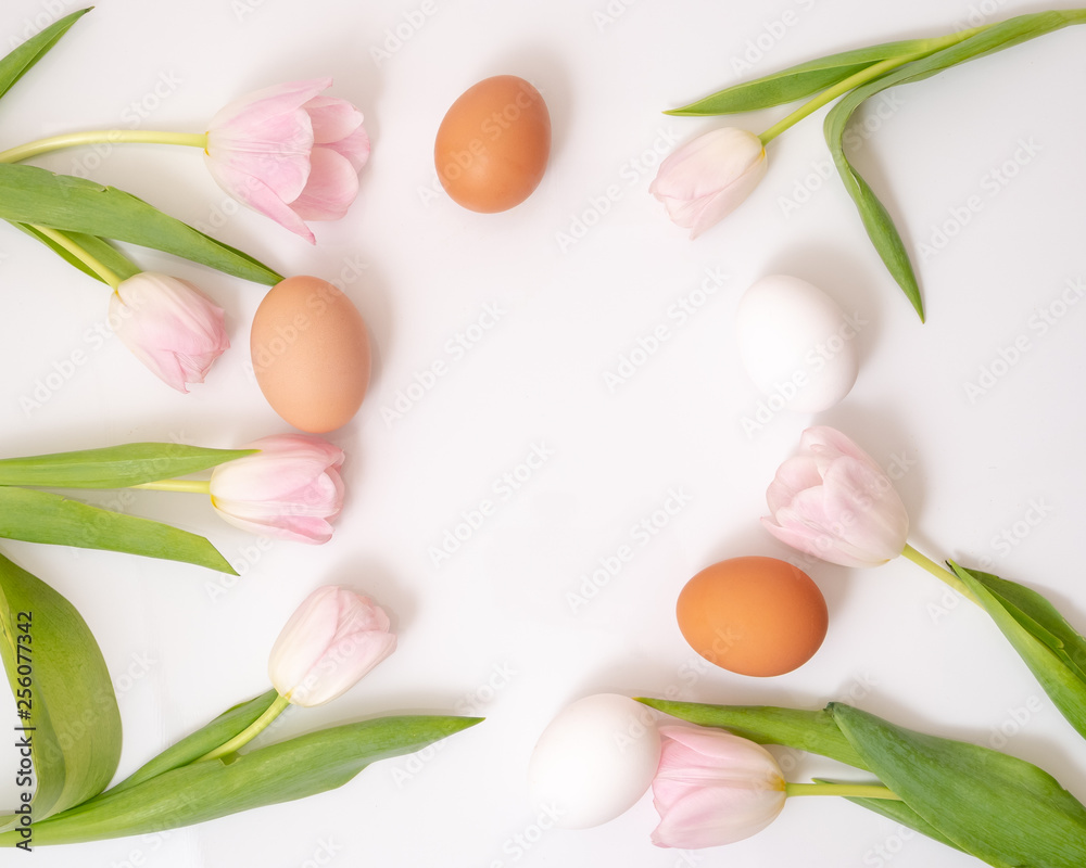 three colored eggs are mixed with pink tulips. Top view three colored eggs are mixed with pink tulips. Top view