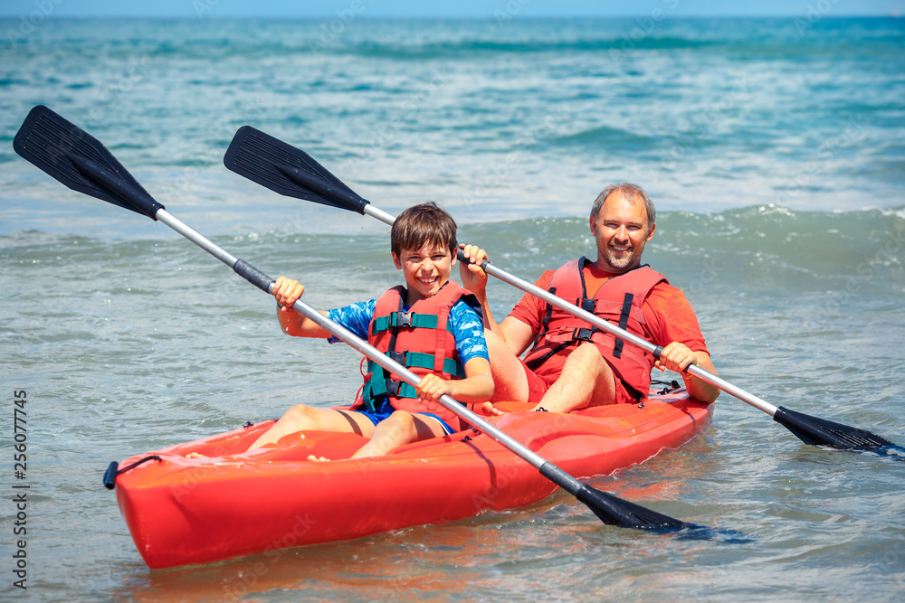 Father and son kayaking in ocean. Active vacation with young kid. Holiday activity with schoolboy child
