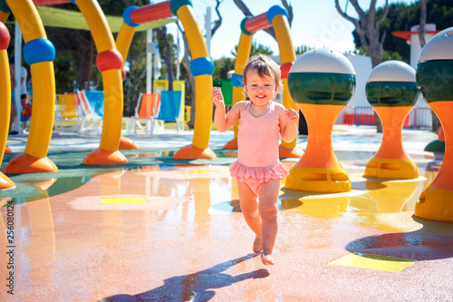 Adorable toddler girl having fun in aquapark. Enjoying day trip to an aqua amusement park