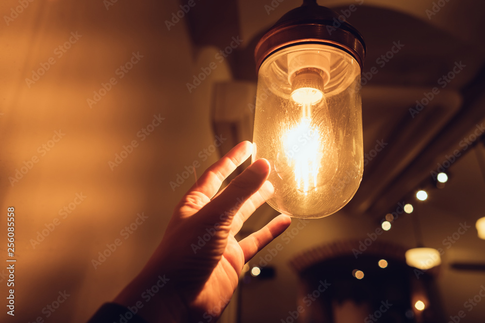Hand reaching for a vintage light bulb.