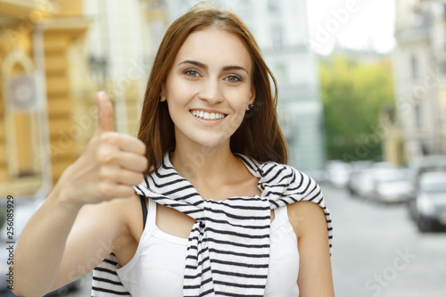 Great! Beautiful young female shows thumbs up smiling looking to the camera