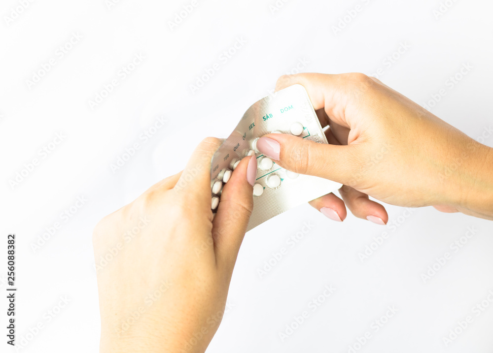 Woman hand holding oral contraceptive pill with white pills white background. Days of the week in Portuguese. Brazil. Woman hand holding oral contraceptive pill with white pills white background. Days of the week in Portuguese. Brazil.