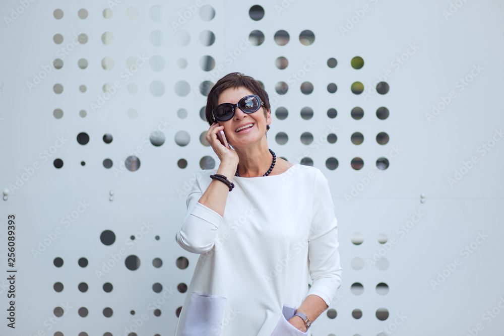 Stylish aged woman speaking on phone on street Stylish aged woman speaking on phone on street