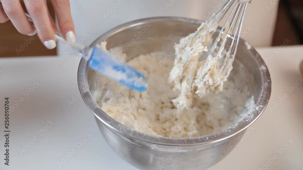 The girl kneads the dough whisk, removes the dough in the whisk. Homemade cake The girl kneads the dough whisk, removes the dough in the whisk. Homemade cake